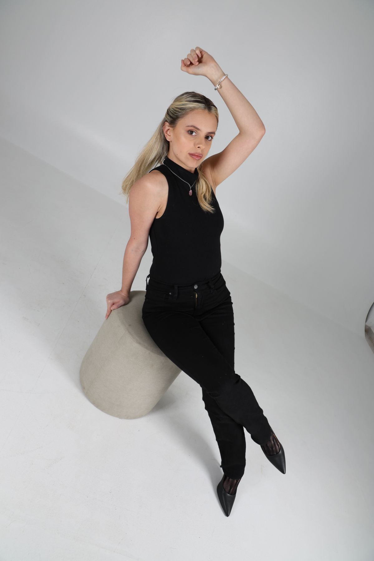 Martina vestida de negro, sentada sobre un volumen claro.