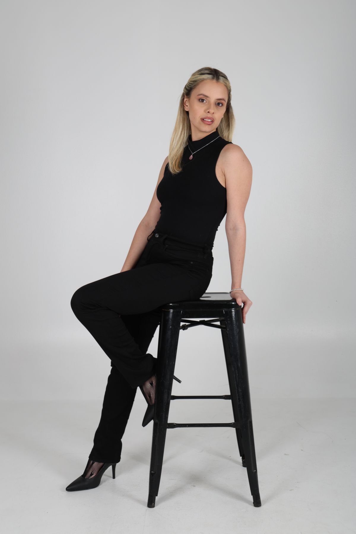 Martina sentada en un banco alto, vestida de negro.