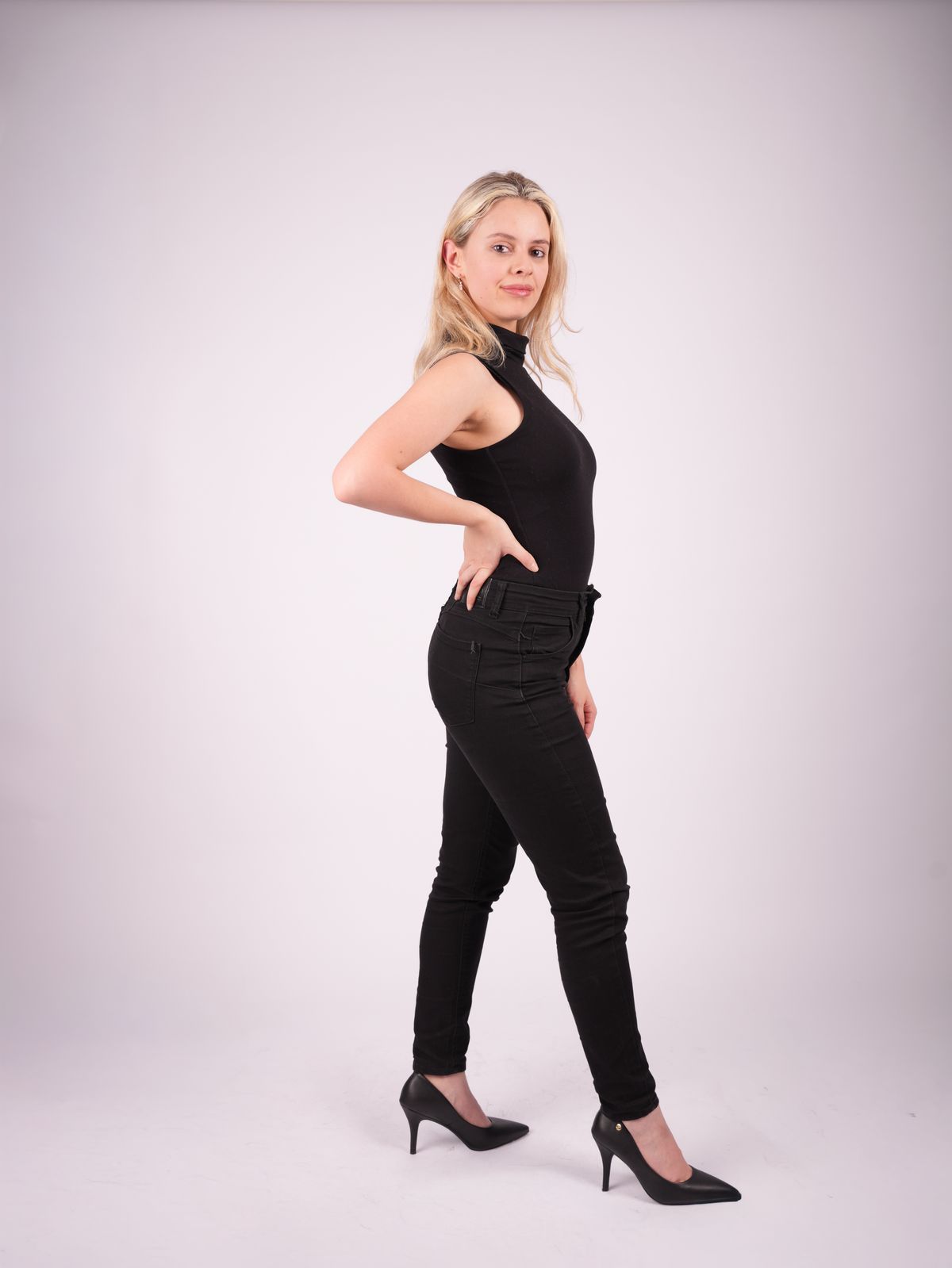 Martina de tres cuartos con conjunto negro y una mano en la cintura.