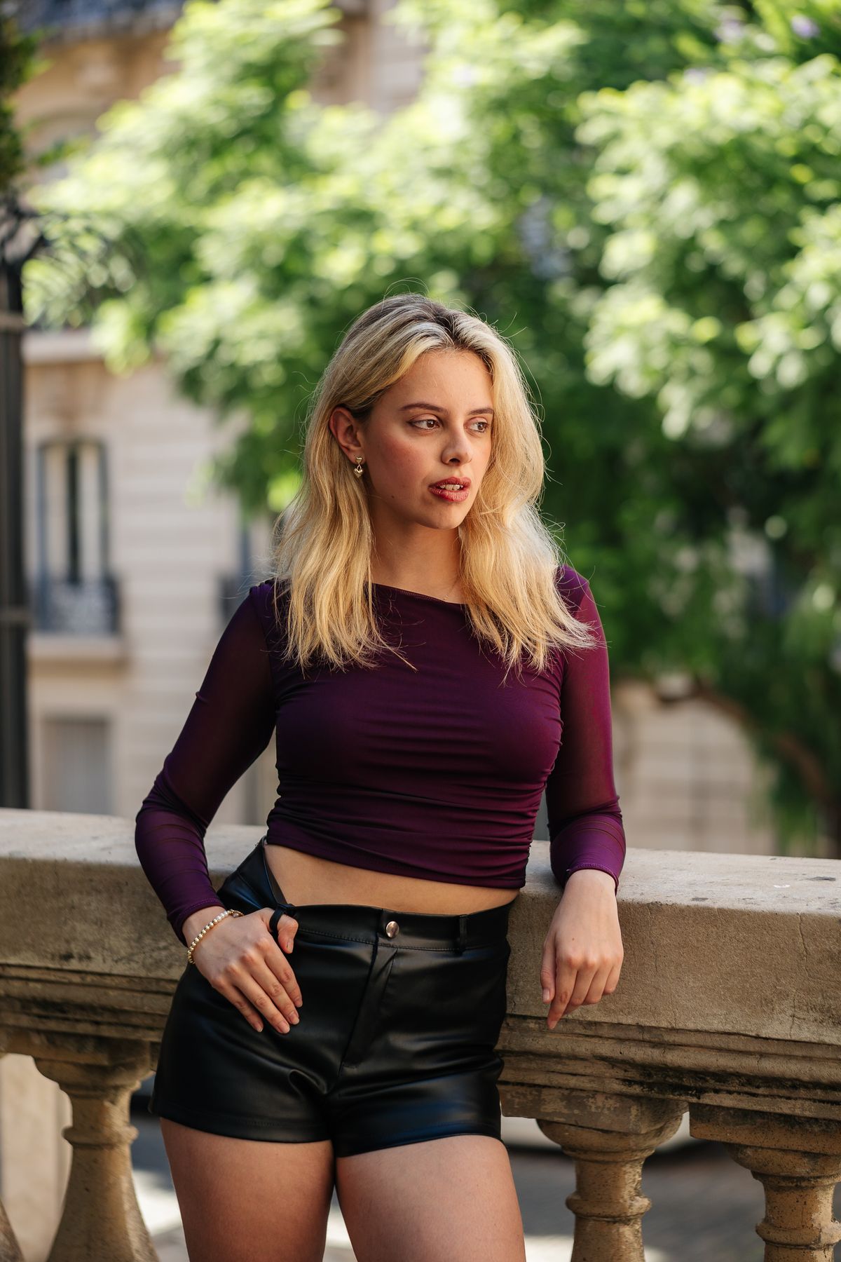 Martina con top bordó y short negro junto a una terraza arbolada.