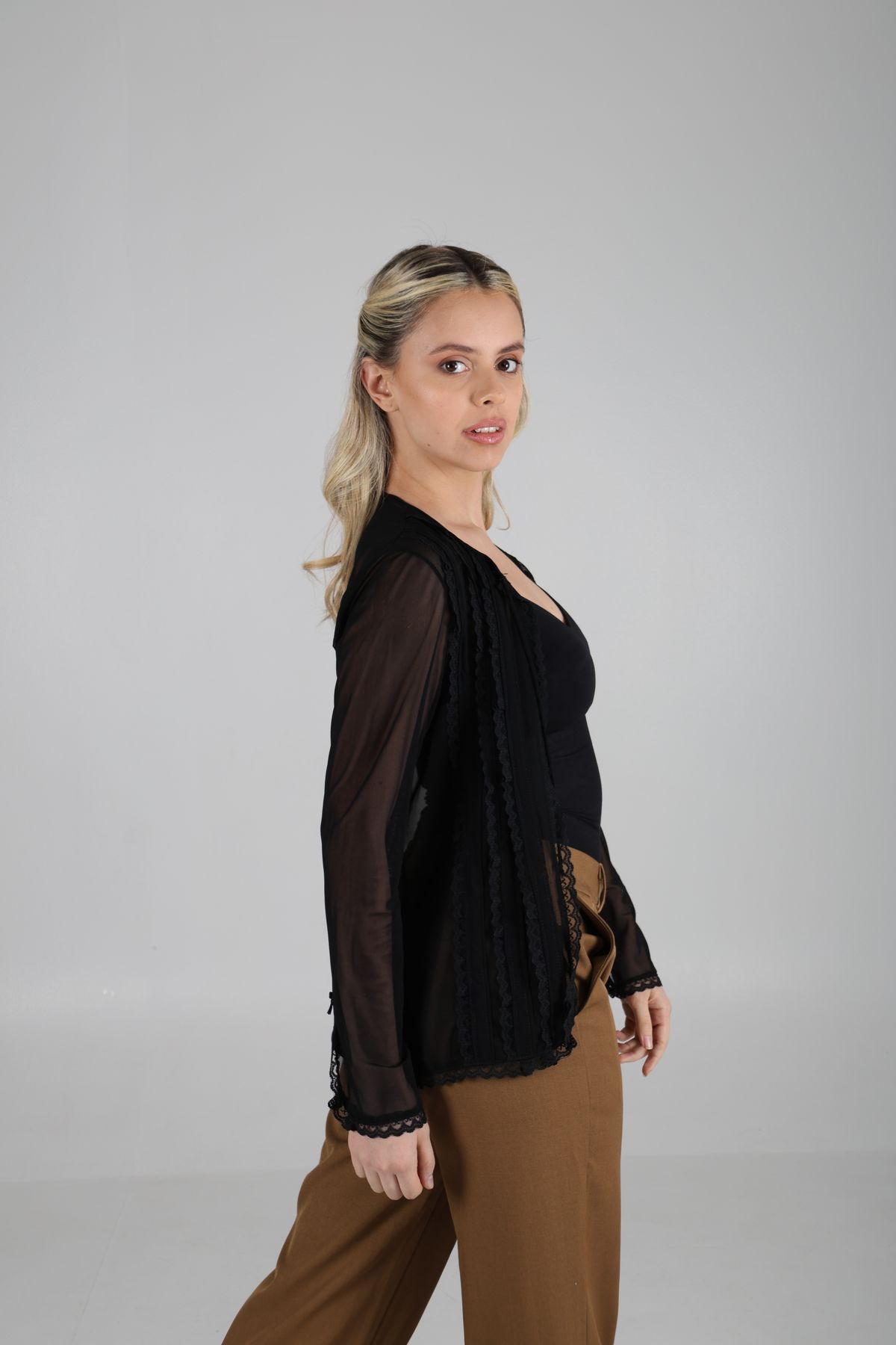 Martina de perfil con blusa negra sobre fondo claro.