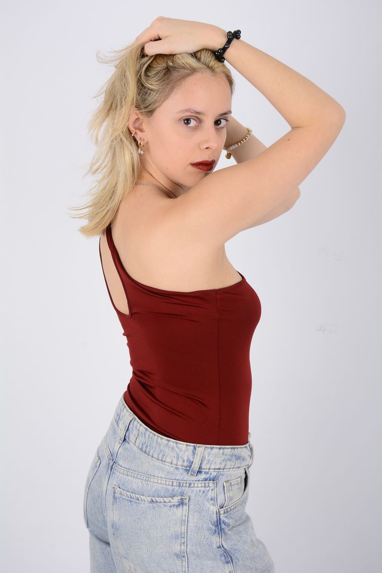 Martina con top rojo y jean, con los brazos sobre la cabeza.