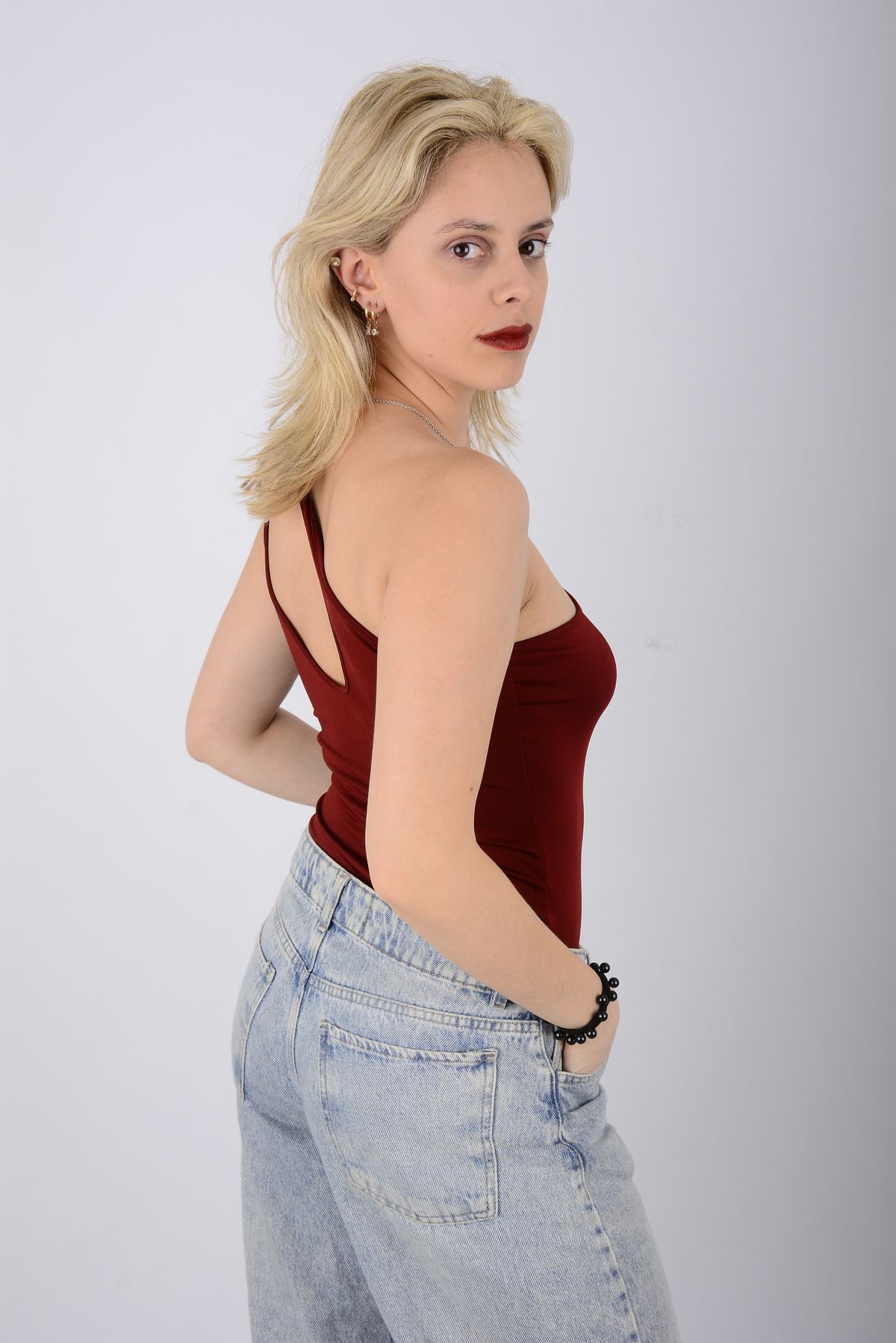 Martina mira hacia atrás con top rojo y jean.