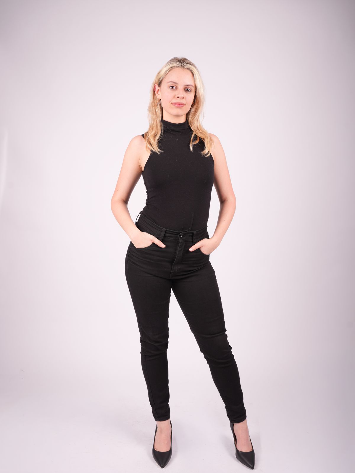 Martina de cuerpo entero con conjunto negro sobre fondo rosado.