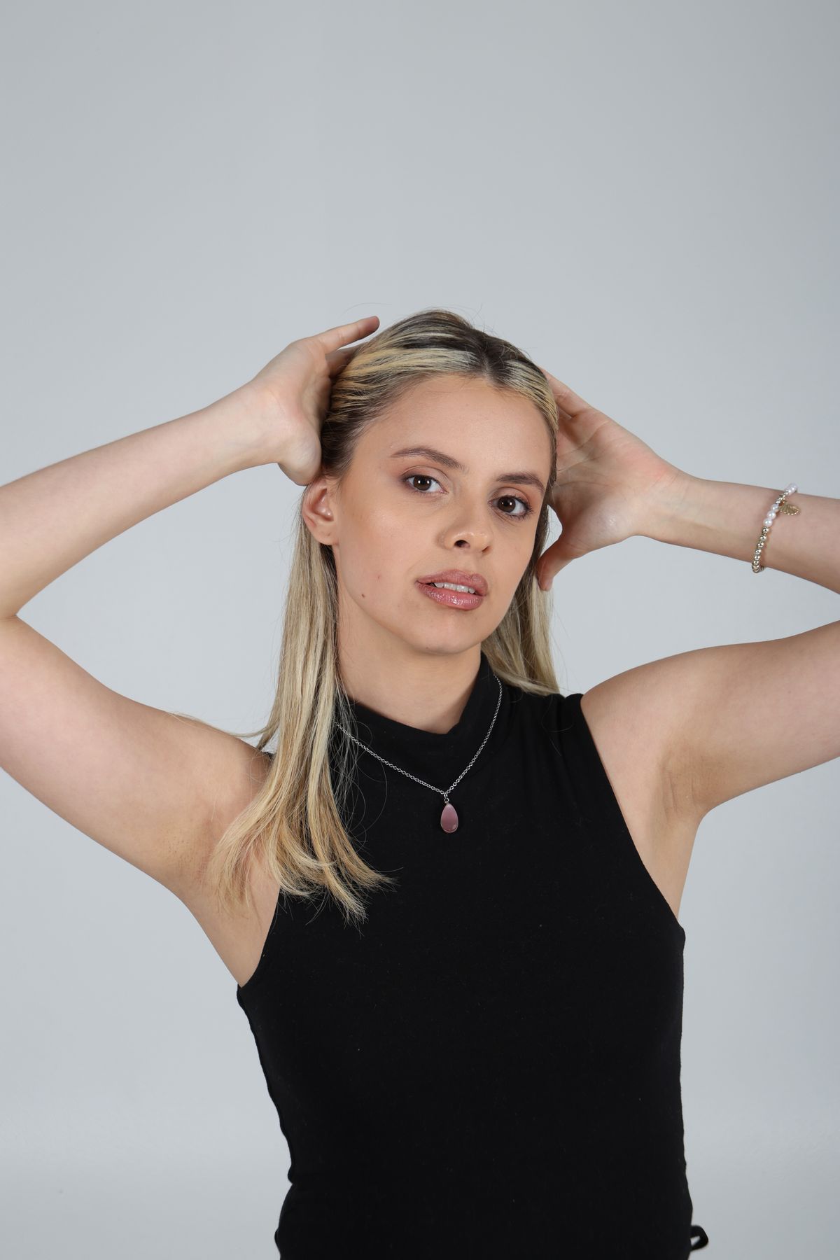Martina posa con top negro y los brazos detrás de la cabeza.