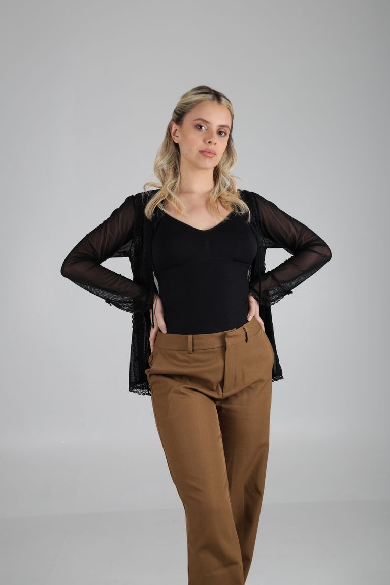 Martina de cuerpo entero con blusa negra y pantalón camel.