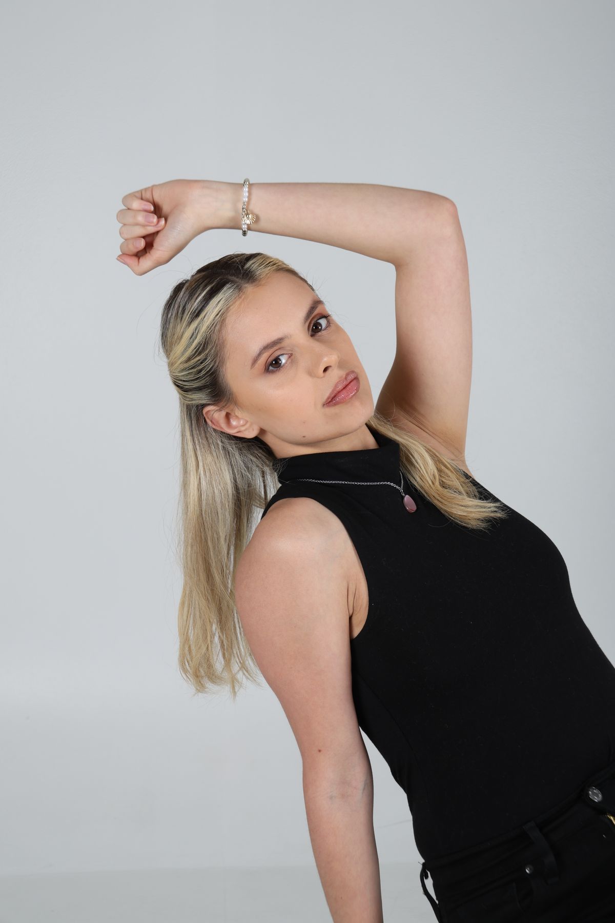 Martina posa sentada de perfil con un brazo sobre la cabeza.