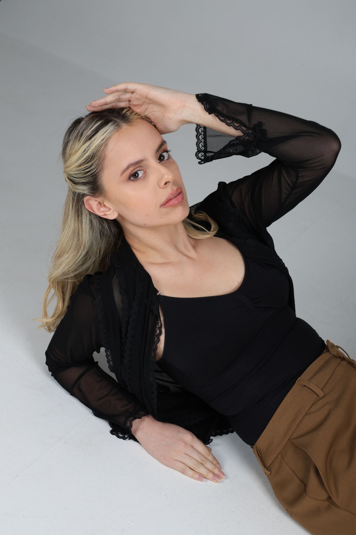 Martina recostada con blusa negra y pantalón camel.