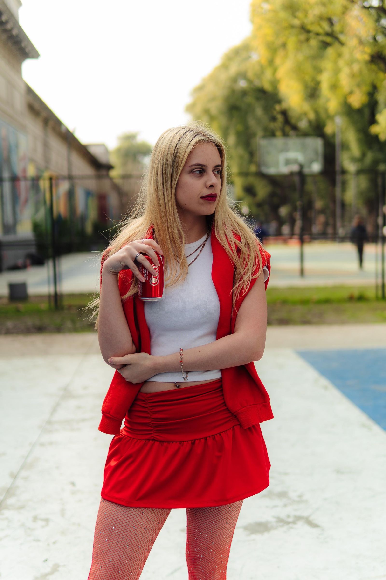 Martina con conjunto rojo en una cancha exterior, mirando hacia un lado.