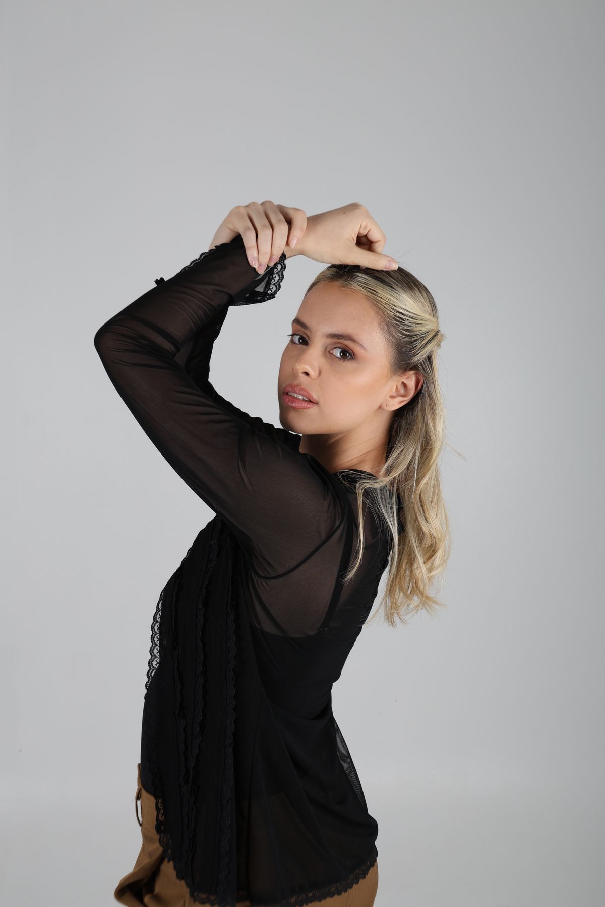 Martina de tres cuartos con blusa negra y las manos sobre la cabeza.