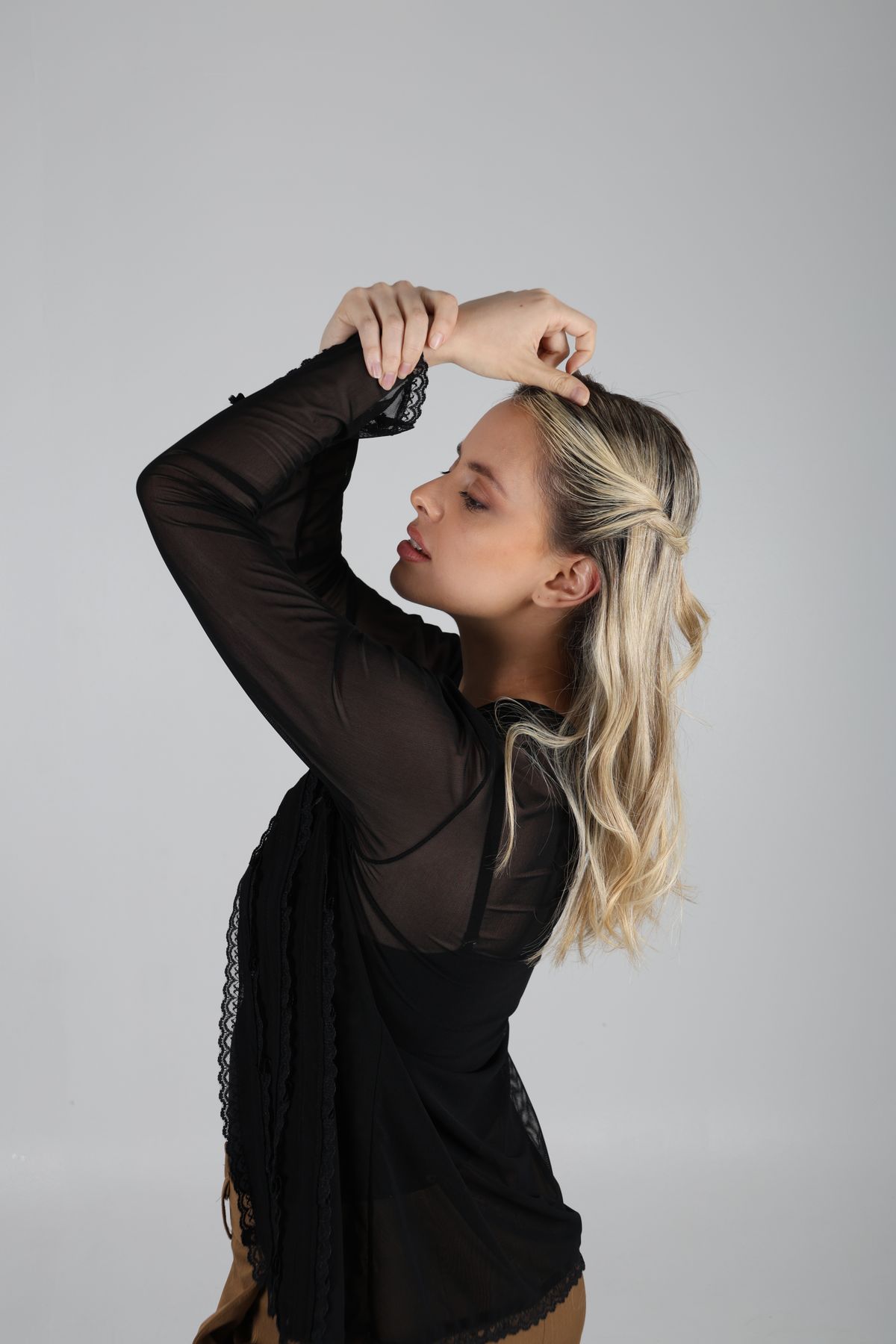 Martina de perfil con blusa negra y los brazos elevados.