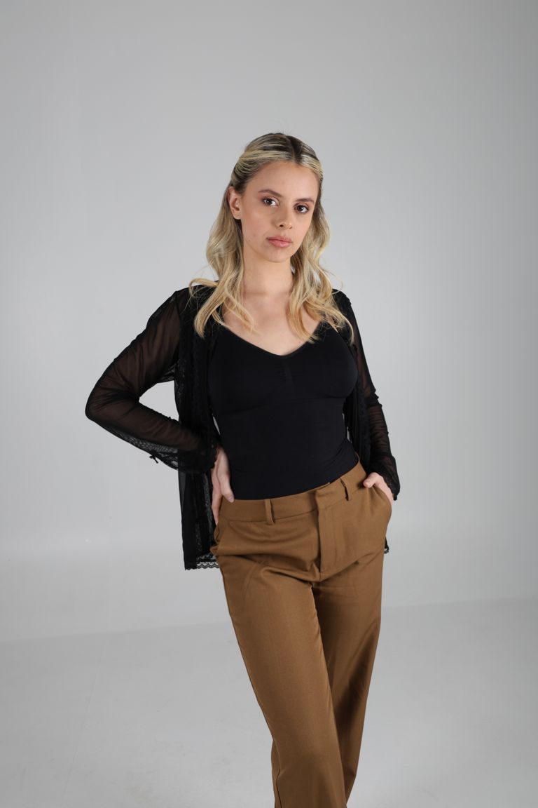 Martina posa de tres cuartos con blusa negra y pantalón camel.
