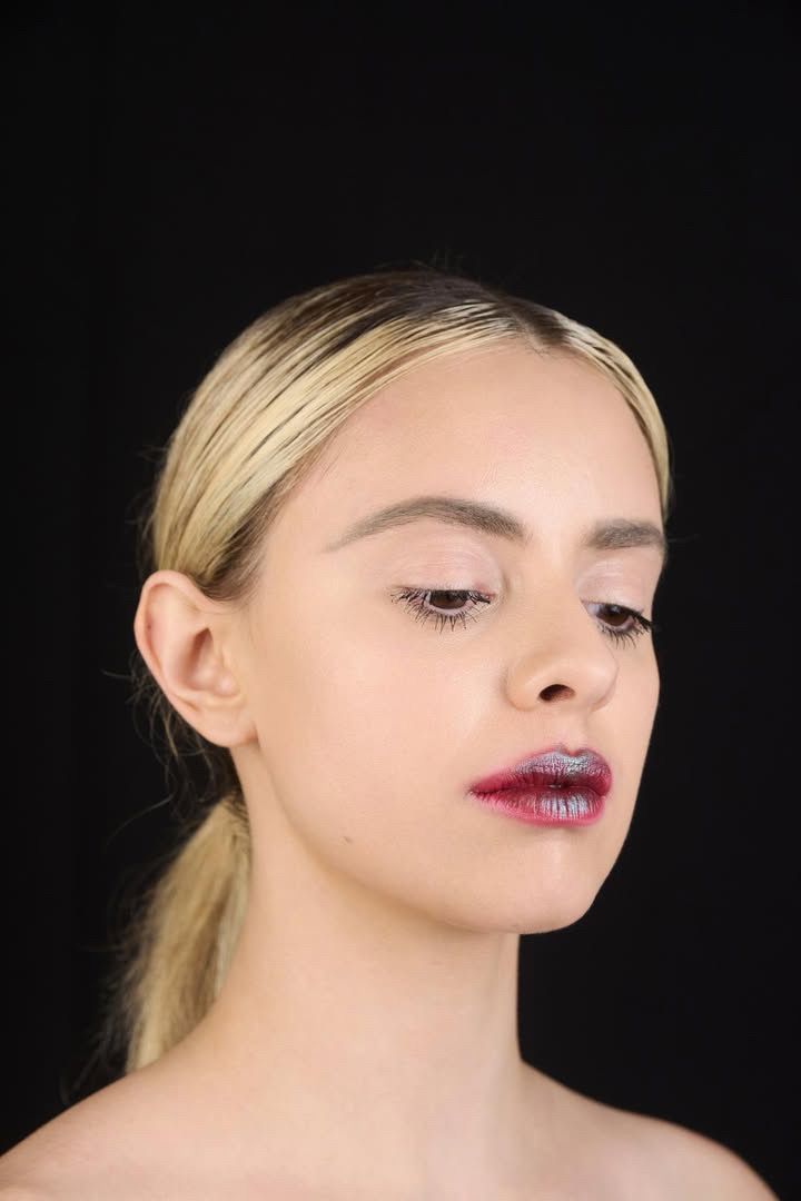 Retrato de Martina con la mirada baja y labios rojos sobre fondo negro.