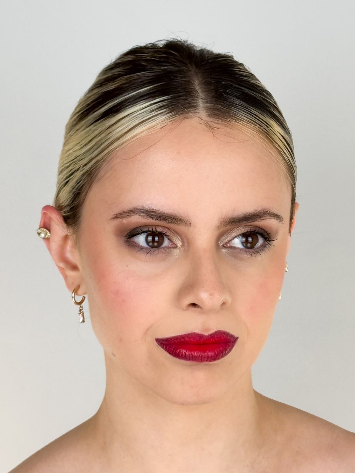 Retrato frontal de Martina con maquillaje de ojos y labios rojos.