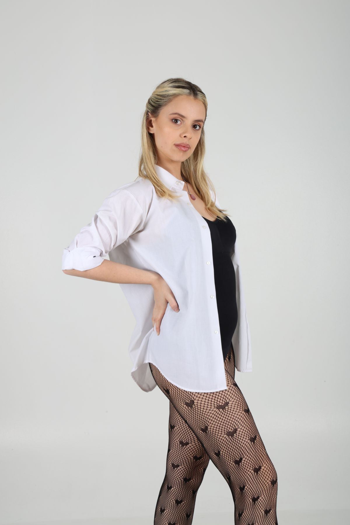 Martina de tres cuartos con camisa blanca y una mano en la cintura.