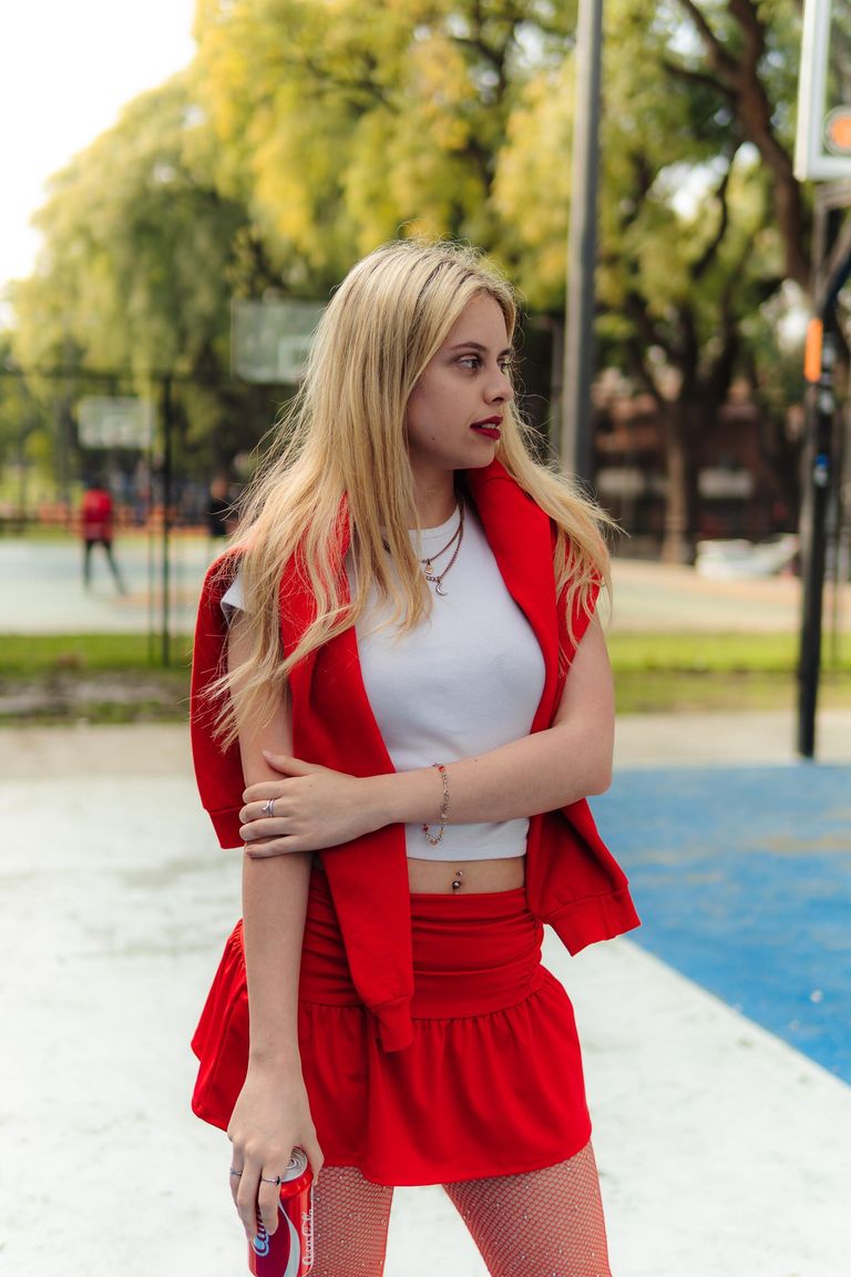 Martina con chaleco y falda rojos en una cancha exterior.