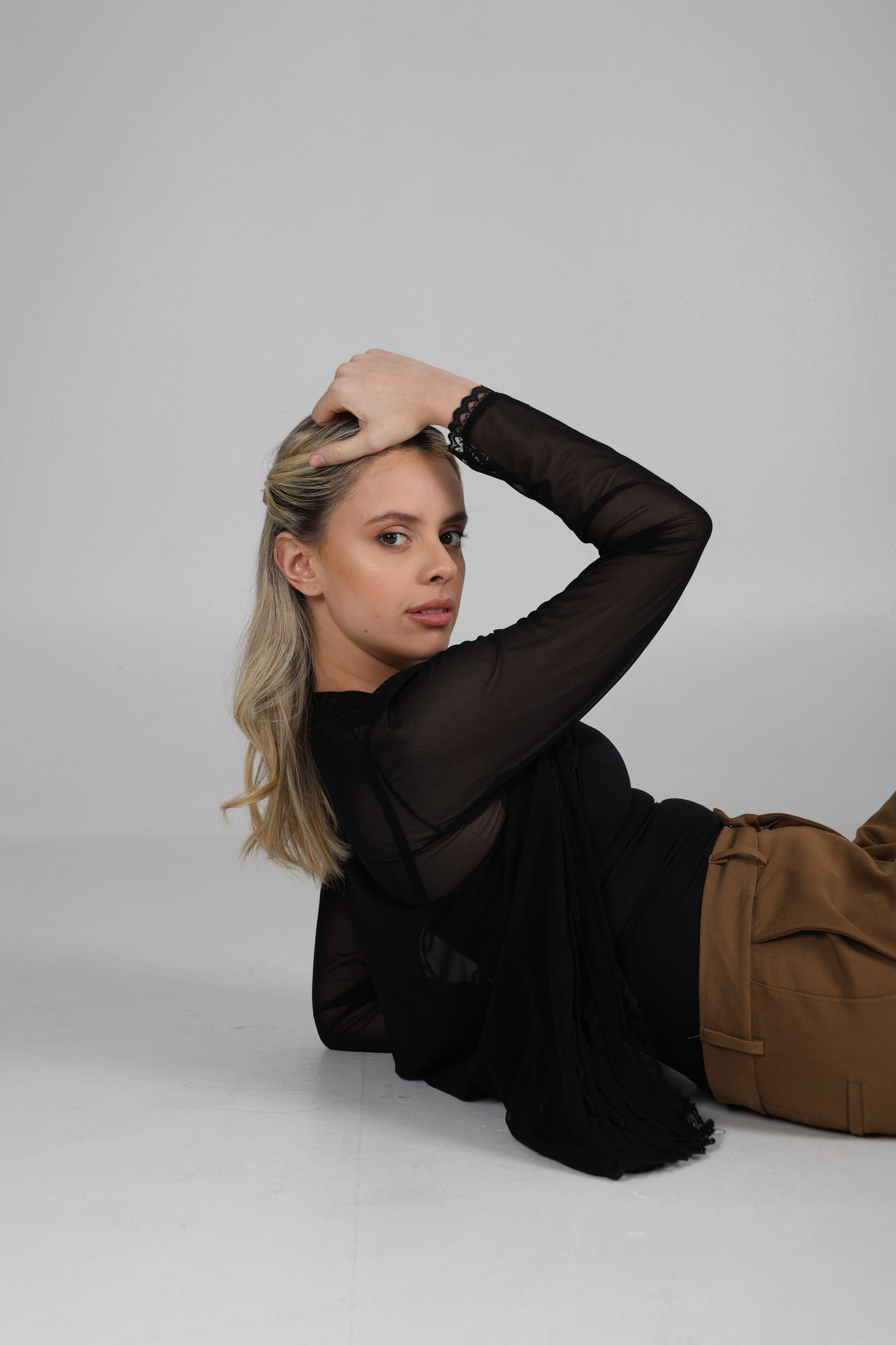 Martina recostada con blusa negra y una mano sobre la cabeza.